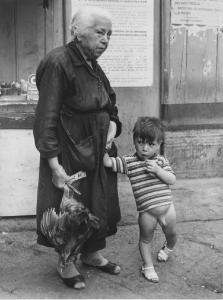 Napoli: Fortuna, fede nella fortuna. Napoli - Vicoli - Ritratto di famiglia - Anziana tiene la mano a un bambino nudo e nell'altra una gallina