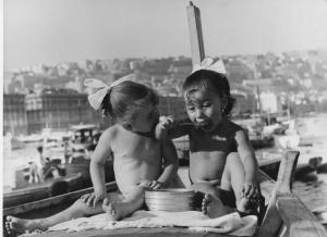 Napoli: Mare/ Bimbi, soli. Napoli, Mergellina - Mare - Ritratto infantile - Bambine nude sedute sulla prua di una barca - Pranzo: cucchiaio in bocca - Fiocco nei capelli