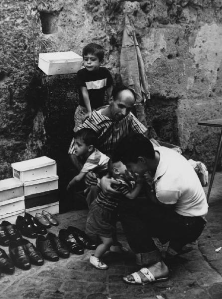Napoli: Commercio. Napoli - Vicoli - Venditore ambulante di scarpe - Due uomini con tre bambini - Gioco