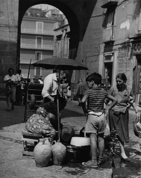 Napoli: Commercio. Napoli - Strada - Venditore ambulante di limonate: donna - Anziani - Bambino - Ombrello