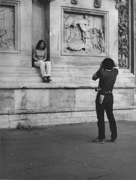 Piazza Duomo. Milano - Piazza del Duomo - Ritratto di coppia - Ragazzo con macchina fotografica e ragazza seduta sul basamento del Duomo