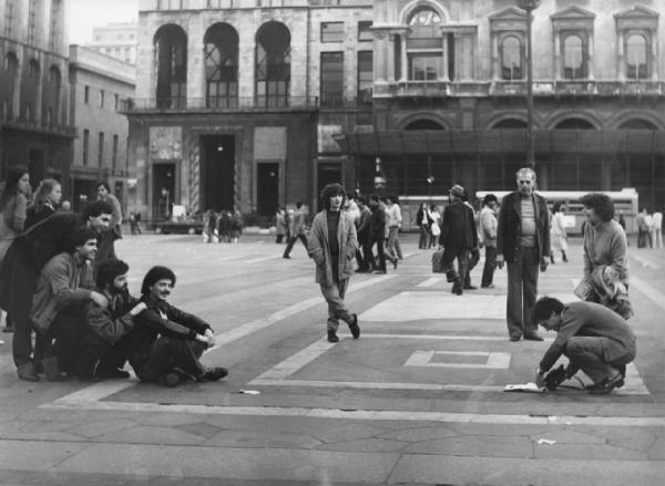 Piazza Duomo: La foto. Milano - Piazza del Duomo - Arengario - Ragazzi in posa davanti a un ragazzo con macchina fotografica - Passanti