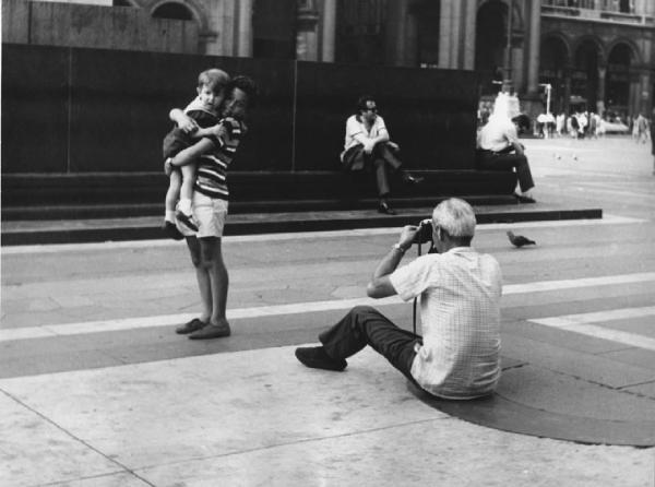 Piazza Duomo: La foto. Milano - Piazza del Duomo - Monumento a Vittorio Emanuele II - Ritratto infantile - Bambino con bambino in braccio in posa - Anziano con macchina fotografica
