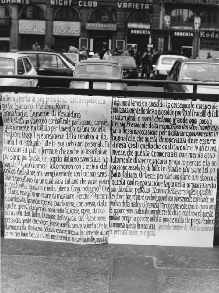 Piazza Duomo: Scritti. Milano - Piazza del Duomo - Ingresso metropolitana - Cartellone con scritta politica e di protesta indirizzata al presidente della Repubblica, Pertini
