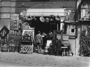 Napoli: Commercio. Napoli - Strada - Negozio di antiquariato - Uomini sulla porta - Sedie, pentole in rame - Vendita oggetti usati