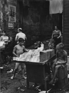 Napoli: Commercio. Napoli - Vicoli - Banco di un venditore ambulante di sigarette da contrabbando: ragazzo con due bambini - Mercato nero