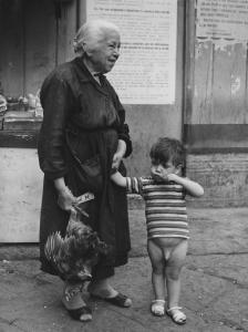 Napoli: Scene di vita varie. Napoli - Vicoli - Ritratto di famiglia - Anziana tiene la mano a un bambino nudo e nell'altra una gallina