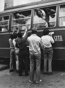 Piazza Duomo: Amore. Milano - Piazza del Duomo - Ragazzi con braccia alzate verso i finestrini di un autobus con ragazze - Addii