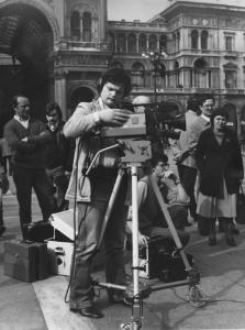 Piazza Duomo: La foto. Milano - Piazza del Duomo - Galleria Vittorio Emanuele - Ragazzo, cineoperatore con cinepresa - Persone in secondo piano