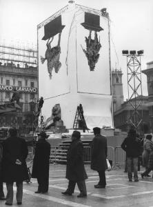 Piazza Duomo: La piazza. Milano - Piazza del Duomo - Monumento a Vittorio Emanuele II coperto da manifesti raffiguranti il monumento sottosopra - Installazione opera d'arte con operai