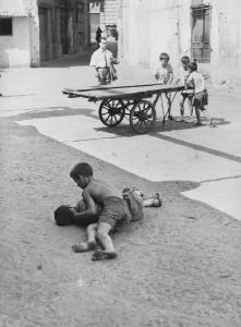 Napoli: Bimbi, scene di vita varie. Napoli - Vicoli - Coppia di bambini a terra - Bambini sullo sfondo con carretto - Gioco