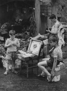 Napoli: Bimbi, scene di vita varie. Napoli - Vicoli - Venditori ambulanti di piccoli oggetti: bambini - Negozio sullo sfondo