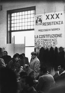 Italia: manifestazioni operai Fiat. Milano - Fabbrica Leyland Innocenti occupata - Interni - Assemblea - Gruppo di operai, uomini - Manifesto FLM