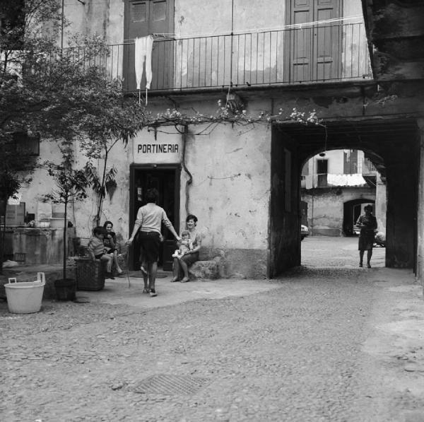 Milano - Alzaia Naviglio Grande 46 - Casa di ringhiera, cortile interno - Insegna con scritta: "portineria" - Ritratto di gruppo: donne e bambini davanti alla portineria