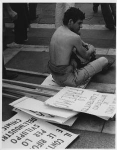 Italia: manifestazione dei chimici. Milano - Piazza del Duomo - Manifestazione operai industria chimica - Manifestante, ragazzo seduto su cartelli di protesta