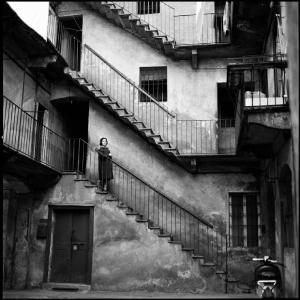 Milano - Piazza Lega Lombarda 5 - Casa di ringhiera: cortile interno, scale - Ritratto femminile: donna che scende le scale - Motorino parcheggiato