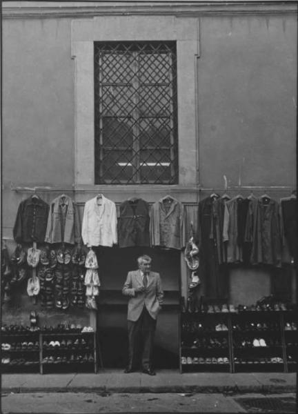 Firenze - Strada - Giacche appese al muro - Scarpe - Ritratto maschile a figura intera: Lorenzo M., calzolaio sull'ingresso del negozio