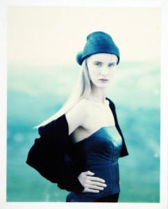 Campagna pubblicitaria per Trussardi Donna - Esterno: paesaggio bucolico - Modella di profilo con mani sui fianchi: top in pelle nera e cappello