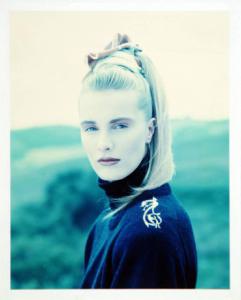 Campagna pubblicitaria per Trussardi Donna - Esterno: paesaggio bucolico - Modella con maglione a collo alto e ricamo sulla spalla - Coda alta