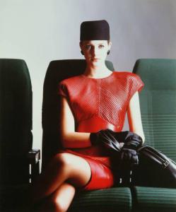Campagna pubblicitaria per Trussardi Donna - Modella con abito di pelle rossa - Cappello, orecchini, guanti e borsa neri - Poltrone verdi Alitalia