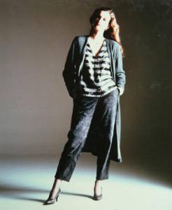 Campagna pubblicitaria per Trussardi Donna - Collezione Donna Autunno/Inverno 83/84 - Modella a figura intera: pantaloni di pelle scamosciata violacea, maglia a righe, cardigan lungo