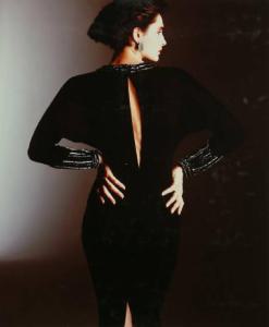 Campagna pubblicitaria per Trussardi Donna - Collezione Donna Autunno/Inverno 85/86 - Modella di schiena - Volto di profilo - Abito da sera nero con scollo posteriore e spacco