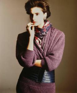 Campagna pubblicitaria per Trussardi Donna - Modella con braccia incrociate e mano sul mento: vestito di maglia viola con cinturone nero e foulard fantasia