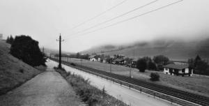 Brennero. Binari della ferrovia e strada carrozzabile corrono affiancati lungo un fondovalle alpino - abitazioni