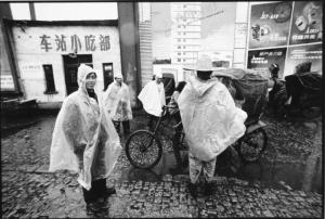 Giovani cinesi indossano mantelline impermeabili - guidatori di rickshaw