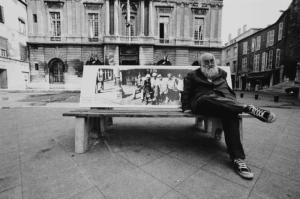 Anziano seduto su una panchina in una piazza cittadina