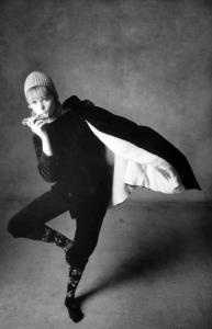 Campagna fotografica per "Arianna" - modella indossa un completo di velluto scuro con pantaloni alla zuava e giacca alla coreana - porta un cappello di maglia, calze fiorate e suona un'armonica a bocca