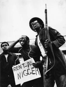 New York - Harlem - attivisti politici con moschetto e cartello con la scritta "rent-a-nigger"