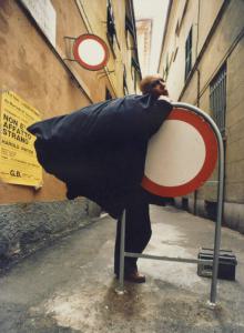 Genova. Attore appoggiato a un cartello di divieto d'accesso - locandina dello spettacolo teatrale "Non è affatto strano"