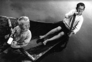 Due bambini a caccia di vermi a bordo di un'imbarcazione a remi