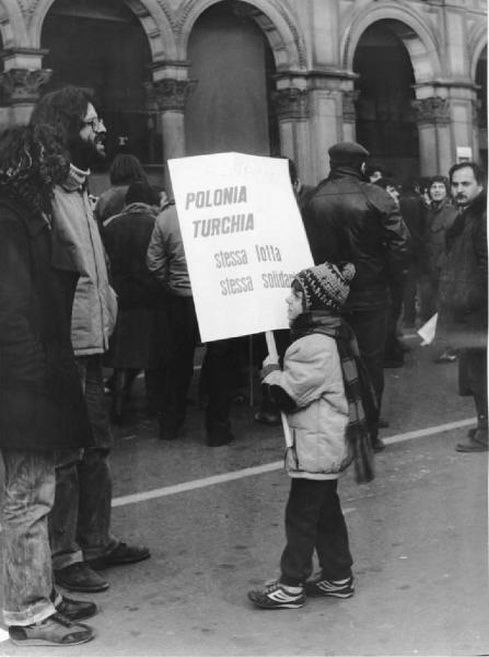 Piazza Duomo: Scritti. Milano - Piazza del Duomo - Manifestazione - Manifestanti - Bambino con un cartello a favore di Salvador, Polonia e Turchia