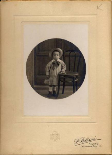 Ritratto infantile - Bambino in divisa accanto a una sedia / Milano - Istituto Derelitti di via Settembrini