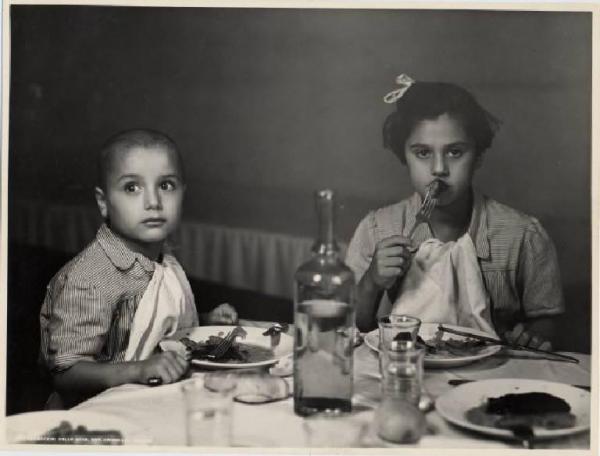 Ritratto di gruppo - Bambino e ragazza a tavola / Milano - Istituto di Assistenza ai Minorenni di via Venini