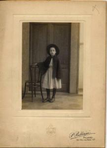 Ritratto infantile - Bambina in divisa accanto a una sedia / Milano - Istituto Derelitti di via Settembrini