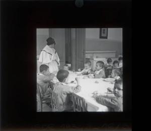 Ritratto di gruppo - Bambini a tavola con Suore di Carità / Milano - Istituto di Assistenza ai Minorenni di via Settembrini - Refettorio
