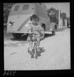 Ritratto infantile - Famiglia Barbieri - Bambina su bicicletta a rotelle - Automobile in sosta