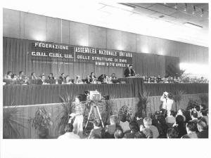 Assemblea nazionale unitaria delle strutture di base - Interno - Palco - Tavolo della presidenza con oratori - Luciano Lama al microfono - Parola d'ordine