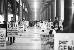 Manifestazione contro la guerra civile in Biafra - Corteo sotto i portici di piazza del Duomo - Cartelli di protesta