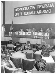 VIII congresso provinciale della Fim Cisl - Interno - Tavolo della presidenza - Pierre Carniti al microfono - Parola d'ordine - Bandiera Flm