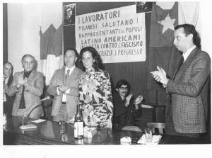 Camera del Lavoro - Sala "Bruno Buozzi" - Interno - Incontro con una delegazione dei popoli latino-americani - Tavolo della presidenza con G. Scarpino, rappresentante cilena e L. De Carlini - Bandiere - Parola d'ordine - Ritratto di Salvador Allende