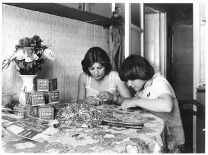 Abitazione - Interno - Lavoro in nero a domicilio - Donna e figlia lavorano intorno a un tavolo
