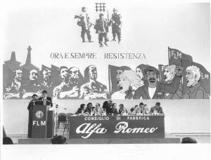 Fabbrica Alfa Romeo di Arese - Interno - Assemblea dei lavoratori delle aziende a partecipazione statale - Tavolo della presidenza con oratori - Murales "Ora e sempre resistenza" - Stemma Alfa Romeo