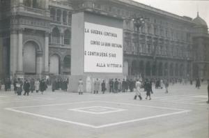 Veduta architettonica. Milano - Piazza del Duomo - Scritta di propaganda bellica allestita sui portici meridionali