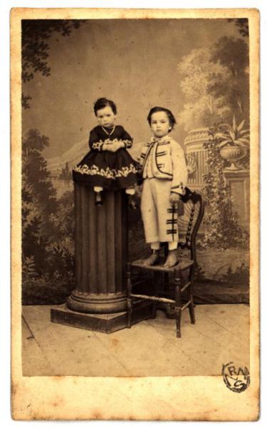 Ritratto di famiglia (?) - Una bambina seduta su un piedistallo e un bambino in piedi su una sedia (fratelli?)