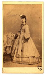 Ritratto femminile - Giovane con cappello e ombrello in piedi, accanto a una poltrona