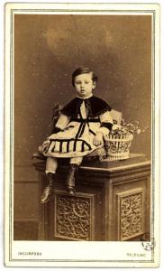 Ritratto infantile - Bambina seduta su un piedistallo con una pianta accanto